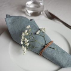 a white plate topped with a blue napkin and flowers on top of it next to a fork