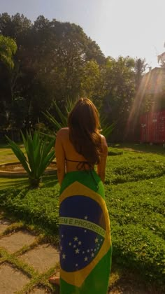 a woman in a green and yellow dress is looking out at the grass with her back to the camera