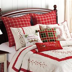 a bed with red and white comforters and pillows