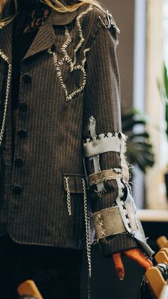 a close up of a person wearing a jacket with chains on the sleeves and cuffs