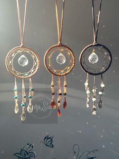 three necklaces hanging from the ceiling with glass beads and crystal stones on each one