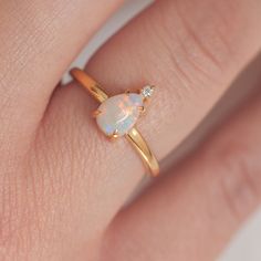 a woman's hand with an opal and diamond ring