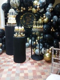 black and gold decorations are on display in front of a large balloon wall with balloons