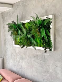 a living room with a pink couch and green plants on the wall above it,