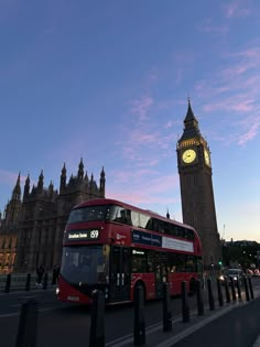 a red double decker bus driving past the big ben clock tower