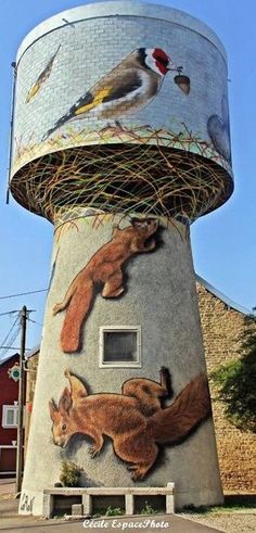 a tall tower with animals painted on it's sides and birds flying around the top