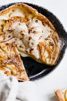 an apple pie is on a black plate with a slice cut out and covered in powdered sugar