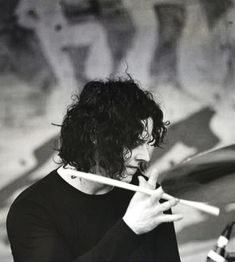 a man with long curly hair playing drums