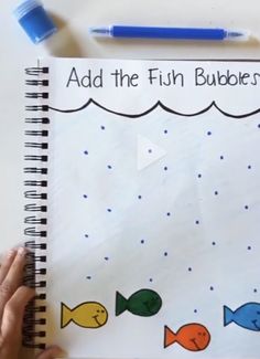 someone is holding a notebook with an image of fish and bubbles on the cover, which reads add the fun bubbles