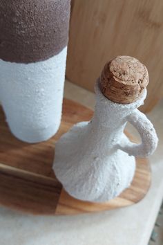 two white and brown vases sitting on top of a wooden board