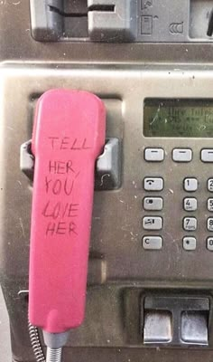 an old pay phone with writing on it and a pink cord attached to the telephone