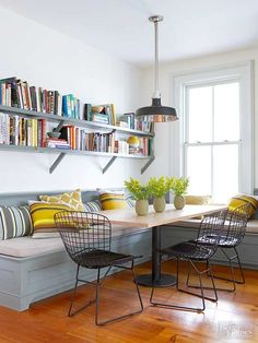 a dining room table with chairs and bookshelves on the wall in front of it