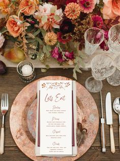 a table setting with place settings, silverware and floral centerpieces on it