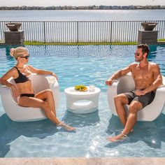 a man and woman sitting in chairs next to a swimming pool