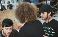 two men are talking to each other in front of a skateboard ramp at an event