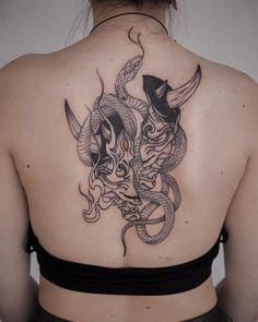 the back of a woman's shoulder with a dragon and snake tattoo on it