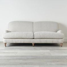 a couch sitting on top of a wooden floor next to a white wall and hardwood floors