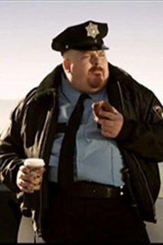 a man in a police uniform holding a drink and cell phone