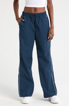 Throwback '70s style and a useful watrer-repellent finish lend style and function to these sporty nylon pants embroidered with a classic Swoosh logo. 30" inseam; 21" leg opening; 13" front rise; 16" back rise (size Medium) Elastic/drawstring waist Side-seam welt pockets; back welt pocket Water repellent 100% nylon Machine wash, tumble dry Imported Nike Sports Bottoms In Nylon, Nike Nylon Sports Bottoms, Nike Sporty Go-dry Pants, Sporty Parachute Pants For Outdoor, Nylon Sports Trousers, Nike Stretch Nylon Bottoms, Nike Nylon Bottoms With Elastic Waistband, Go-dry Nylon Bottoms For Streetwear, Sporty Nike Nylon Pants