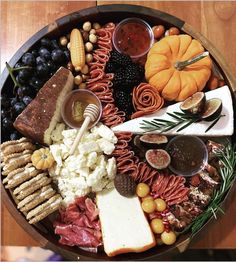 a wooden platter filled with different types of cheeses and meats on top of it