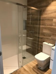 a bathroom with a toilet, shower and wooden flooring on the side of the wall