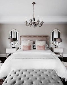 a white bed sitting under a chandelier in a bedroom