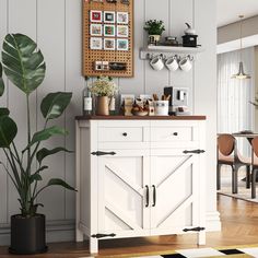 a kitchen with white cabinets and wooden floors, potted plants on the counter top