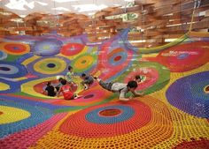 an art installation made out of crochet and yarn with people working on it