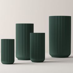 three green vases sitting next to each other on a white surface with no one around them