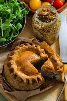 a pie sitting on top of a wooden cutting board next to a bowl of vegetables