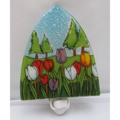 a glass toothbrush holder with flowers painted on the front and bottom, hanging from a wall