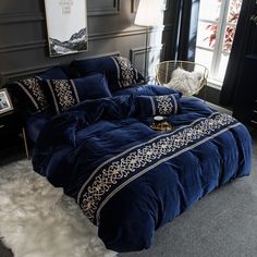 a bed with blue comforter and pillows in a room next to a window,