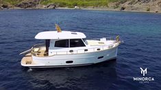 a white boat floating on top of a body of water next to a rocky shore