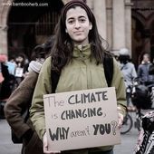 a woman holding a sign that says the climate is changing why aren't you?