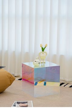 a glass table with flowers on it in front of a window