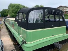 a green and black boat is docked in the water