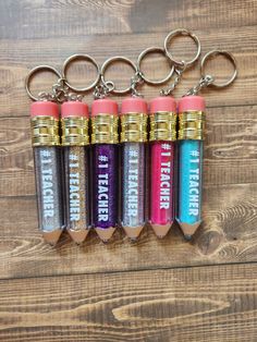 four different colored pencils with the words teacher on them hanging from a keychain