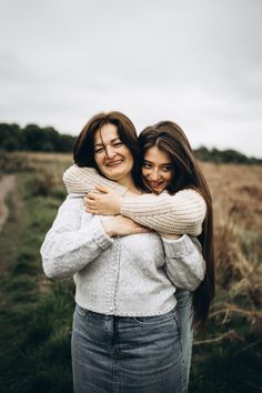 two women hugging each other in the middle of a field