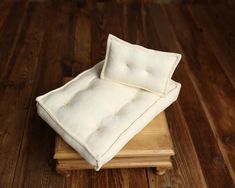 two white pillows sitting on top of a wooden platform in a room with wood floors