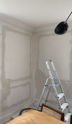 a ladder is in the corner of a room that has been painted with white paint