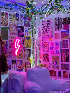 a living room filled with lots of pink and white furniture covered in posters on the wall