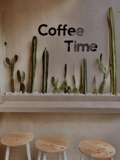 three stools in front of a coffee time sign with cacti on it