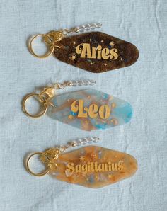 three keychains with the name aries and zodiacs written on one side