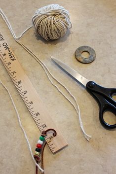 a pair of scissors next to a measuring tape and some twine on the floor