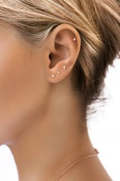 a woman with ear piercings on her left side, wearing a gold necklace and earrings