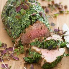 a piece of meat covered in herbs on a cutting board