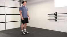 a man standing in front of a garage door wearing black shorts and a blue t - shirt