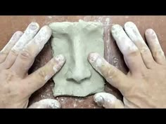 two hands that are making some kind of face out of clay on a table with flour all over it