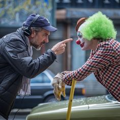 two clowns standing next to each other pointing at something on the ground in front of them