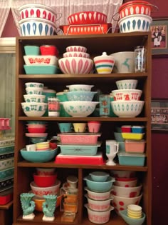 a wooden shelf filled with lots of colorful dishes